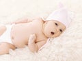 Sweet baby in hat yawns on the bed Royalty Free Stock Photo