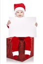 Sweet baby wearing a Santa costume, smiling and sitting on a red Royalty Free Stock Photo