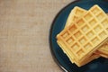 Sweet baked fluted Belgian waffles on a blue ceramic plate and a baggy background