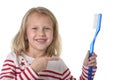 Sweet beautiful female child with blond hair and big blue eyes holding huge toothbrush smiling happy Royalty Free Stock Photo