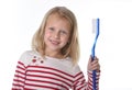 Sweet beautiful female child with blond hair and big blue eyes holding huge toothbrush smiling happy Royalty Free Stock Photo