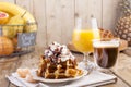 Sweet Belgian waffles for breakfast, decorated with white cream and chocolate sauce. Glass with coffee black and orange juice,