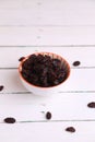 Sweet black dried raisins in the bowl on the wooden surface Royalty Free Stock Photo