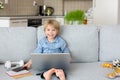 Sweet blond child, boy in casual clothes, woring on computed at home