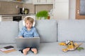 Sweet blond child, boy in casual clothes, woring on computed at home