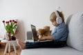 Sweet blond child, boy in casual clothes, woring on computed at home