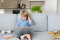 Sweet blond child, boy in casual clothes, woring on computed at home