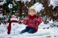 Sweet blond toddler child, boy, playing in garden with snow, making snowman, happy kid winter time Royalty Free Stock Photo
