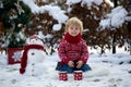 Sweet blond toddler child, boy, playing in garden with snow, making snowman, happy kid winter time Royalty Free Stock Photo