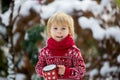 Sweet blond toddler child, boy, playing in garden with snow, making snowman, happy kid winter time Royalty Free Stock Photo