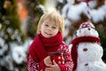 Sweet blond toddler child, boy, playing in garden with snow, making snowman, happy kid winter time Royalty Free Stock Photo