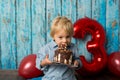 Sweet blond toddler child, boy, playing on his birhtday with toys and little chocolate cake