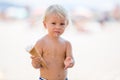 Sweet blonde toddler boy, eaiting ice cream on the beach