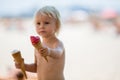 Sweet blonde toddler boy, eaiting ice cream on the beach Royalty Free Stock Photo
