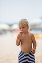 Sweet blonde toddler boy, eaiting ice cream on the beach