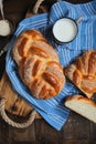 Sweet braided buns with sesame seeds on a blue kitchen towel.