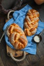 Sweet braided buns with sesame seeds on a blue kitchen towel.