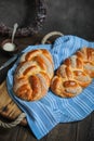 Sweet braided buns with sesame seeds on a blue kitchen towel.