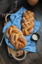 Sweet braided buns with sesame seeds on a blue kitchen towel.