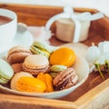 Sweet breakfast in bed for lover. Close up macaroons, cup of coffee, flower and gift box on wooden tray. Romantic breakfast in bed Royalty Free Stock Photo