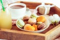 Sweet breakfast in bed for lover. Close up macaroons, cup of coffee, juice, flower and gift box on wooden tray. Romantic breakfast Royalty Free Stock Photo