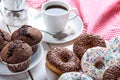 Sweet breakfast with chocolate muffins and donuts, cup of black coffee on white wooden board table. Red dishcloth Royalty Free Stock Photo