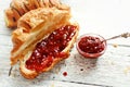 Sweet breakfast. Croissant with raspberries. Raspberry jam in a silver spoon and a bowl. Fragrant pastries on a white wooden