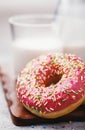 Sweet breakfast: strawberry donut with milk on a wooden stand