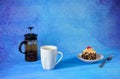 Sweet breakfast, tea cup plate with sponge cake in chocolate chips with cherries and tea teapot on a blue abstract background Royalty Free Stock Photo