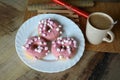 Cup of coffee with milk and three donuts with pink icing on a white plate. Royalty Free Stock Photo