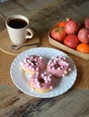 Cup of coffee with milk and three donuts with pink icing on a white plate. Royalty Free Stock Photo