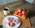 Cup of coffee with milk and three donuts with pink icing on a white plate. Royalty Free Stock Photo