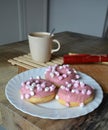 Cup of coffee with milk and three donuts with pink icing on a white plate. Royalty Free Stock Photo