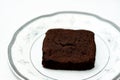 Sweet brownie chocolate cake slice piece with cocoa powder on a white plate isolated on a white background, brownies usually Royalty Free Stock Photo