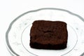 Sweet brownie chocolate cake slice piece with cocoa powder on a white plate isolated on a white background Royalty Free Stock Photo