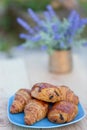 Sweet buns with raisins and croissants on a blue plate and a wooden table and a blurred background, bouquet of lavender