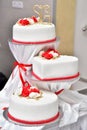Sweet cakes in the form of red roses decorate the wedding cake with more decorative twigs of white cream