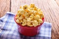 Sweet caramel popcorn in a bowl on blue cotton napkin against wooden background