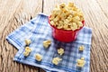 Sweet caramel popcorn in a bowl on blue cotton napkin against wooden background