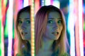 Sweet caucasian girl walks in a mirror maze with colorful diodes and enjoys an unusual attraction room in the city