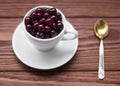 Sweet cherries in a white cup and a teaspoon on a wooden table, selected focus, close up Royalty Free Stock Photo