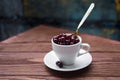 Sweet cherries in a white cup and a teaspoon on a wooden table, selected focus, side view Royalty Free Stock Photo