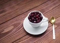 Sweet cherries in a white cup and a teaspoon on a wooden table, selected focus Royalty Free Stock Photo