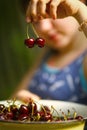 Sweet cherry merry in human hand with teenager girl on background