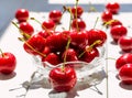 sweet cherry in glass bowl and scattered on white wooden table. Red fresh cherry washed, drops shine Royalty Free Stock Photo