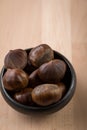 Sweet chestnuts in black bowl on wooden background