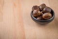 Sweet chestnuts in black bowl on wooden background