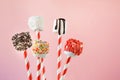 Sweet chewy marshmallow and lollipops on straw decorated with melted chocolate and cake sprinkles on pink background. Kids will lo Royalty Free Stock Photo