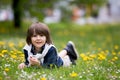 Sweet child, boy, gathering dandelions and daisy flowers