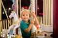 Sweet child, cute blond boy, riding on a merry-go-round, carousel attraction in Europe Royalty Free Stock Photo